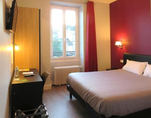 a room with a bed and a desk and a window at Hôtel Le Dormeux in Mehun-sur-Yèvre