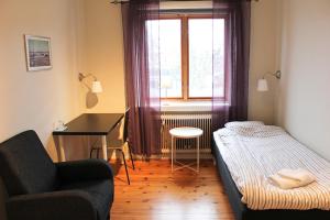 Habitación pequeña con cama, escritorio y ventana. en Blåkråkan Bed & Breakfast en Hemse