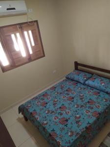 um quarto com uma cama com um edredão azul e uma janela em Chalés Caribe brasileiro - Chale 2 em Maragogi