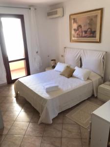 a bedroom with a large white bed and a window at ELAIA HOUSE in Capoterra