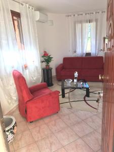 Una sala de estar con un sofá rojo y una mesa. en ELAIA HOUSE, en Capoterra
