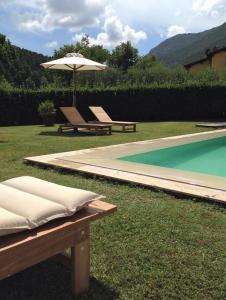 een zwembad met twee banken en een parasol naast een zwembad bij Villa Vaccoli in Lucca