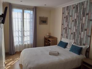 a bedroom with a white bed with blue pillows and a window at Hôtel Roi René in Paris