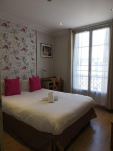 una camera da letto con un grande letto bianco con cuscini rossi di Hôtel Roi René a Parigi