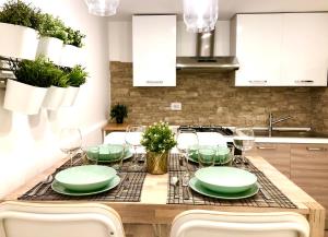 uma mesa de jantar com pratos verdes e copos de vinho em Borgo Empedocle House em Catânia