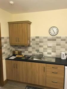 a kitchen with a sink and a clock on the wall at Barbers Hall Apartment Town Center in Belmullet
