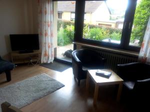 a living room with two chairs and a television and a window at FeWo Gelnhausen in Gründau