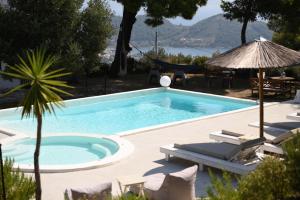 een zwembad met stoelen en een hangmat naast een resort bij Entechnos Living in Skiathos-stad