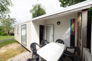 una casa pequeña con una mesa y sillas en una terraza en Camping De La Plage Bénodet - 400 mètres de La Plage, en Bénodet