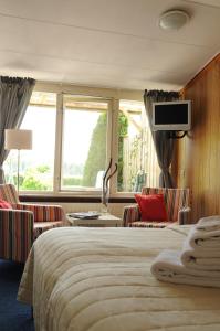 a hotel room with a bed and chairs and a tv at B&B Roodbeekerhof in Vlodrop