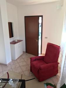 a living room with a red chair and a door at ELAIA HOUSE in Capoterra
