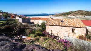 a stone house on a hill with purple flowers at Casa A Laxe in O Pindo