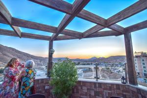 two women standing on a balcony looking out at the city at La Maison Hotel in Wadi Musa