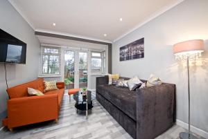 uma sala de estar com um grande sofá e cadeiras laranja em Beautiful Cozy Home With Free Parking em Manchester