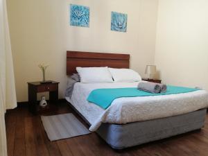 a bedroom with a bed with a blue blanket on it at Hostal Rama & CaStle in Valparaíso