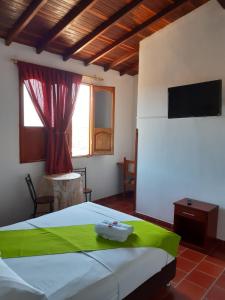 1 dormitorio con 1 cama grande y TV en Posada San Luis, en Páramo
