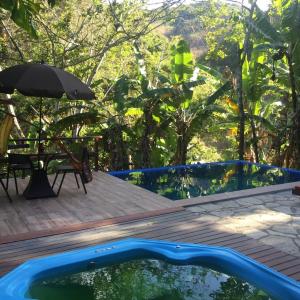 a pool with a table and an umbrella on a deck at Sitio Alto da Montanha - você em paz com a natureza in Pacoti