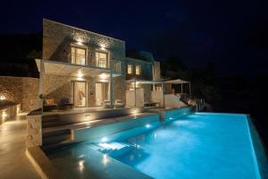 a villa with a swimming pool at night at Katikies Manis Suites in Kardamili