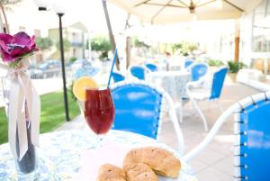 a table with a vase of flowers and a drink at Residence Quadrifoglio in Cervia