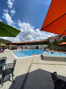 a swimming pool with people in the water and an umbrella at Hotel La Montaña San Gil in San Gil