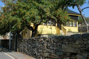 a stone wall and trees in front of a yellow house at Casa da Serra in Penhas da Saúde