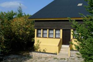 une petite maison jaune avec un toit noir dans l'établissement Casa da Serra, à Penhas da Saúde