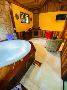 a large bathroom with a tub and a living room at Pousada Magia da Montanha in Visconde De Maua