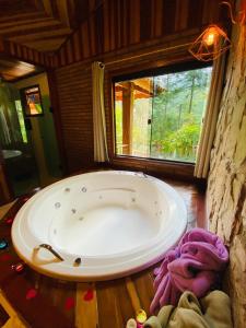 a large bath tub in a room with a window at Pousada Magia da Montanha in Visconde De Maua