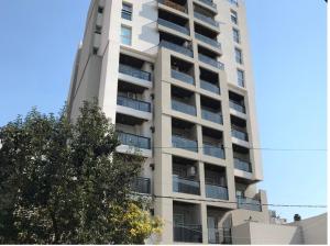 a tall white building with a tree in front of it at Apart del Puerto 01 in Santa Fe