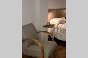 a bedroom with a chair next to a bed at Apart del Puerto 01 in Santa Fe
