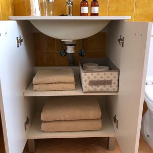 ein Badezimmer mit einem Waschbecken und Handtüchern auf einem Regal in der Unterkunft ATICO SAN MARCOS in El Puerto de Santa María