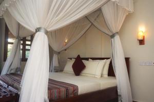 a bedroom with a canopy bed with white curtains at African Roots Gulu in Gulu