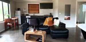 a living room with a black leather couch and a table at Blaze Rock Retreat in Halls Gap