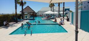 a large swimming pool with people sitting around it at AN OCEAN,BEACHFRONT AND POOL VIEW Apartment 210 in Mandurah