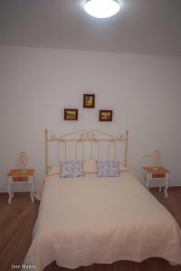 um quarto com uma grande cama branca e duas mesas em Santa Angela de la Cruz em Peñaflor