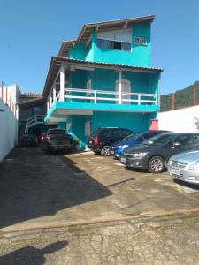 a blue building with cars parked in a parking lot at Dolce Mar Ubatuba Suites in Ubatuba