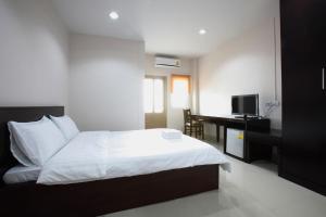 a bedroom with a bed and a desk with a computer at Garden Hill Hotel in Trang +7 photos