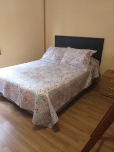 1 dormitorio con cama con manta de flores y cómoda en Casa Sol y Luna en Ushuaia