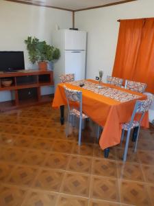 een eettafel met oranje tafelkleed en stoelen bij Casa Sol y Luna in Ushuaia