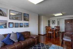 sala de estar con sofá de cuero marrón y mesa en Guernica Apartments, en Lima