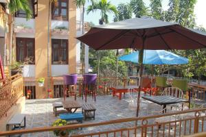 a patio with an umbrella and chairs and tables at Hoi An Golden Horse Villa in Hoi An