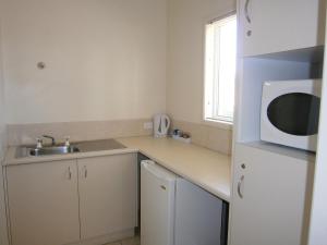a kitchen with a sink and a microwave at Kellys Motel Oakey in Oakey