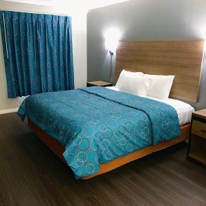 a hotel room with a bed with a blue blanket at Budget Host Inn in Vernon