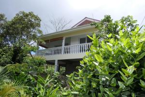 une maison blanche avec une véranda et des arbres blancs dans l'établissement Tropical Garden Self Catering, à Victoria