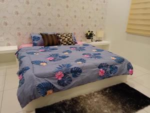 Una cama con un edredón azul con flores. en Permata Hanan Homestay Sungai Petani Kedah, en Kampong Pinang