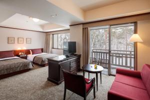 a hotel room with a bed, desk, tv, and chair at Hakuba Tokyu Hotel in Hakuba
