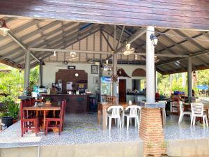an outdoor patio with tables and chairs and a kitchen at Somphoch Garden in Trat