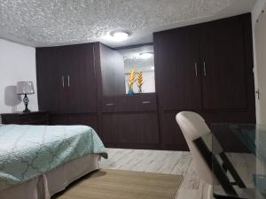 Hill Retreat - Kingston في كينغستون: غرفة نوم بها دواليب خشبية وسرير وكرسي