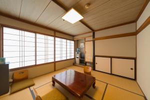 
a living room with a wooden floor and a large window at Shotoen in Yonago
