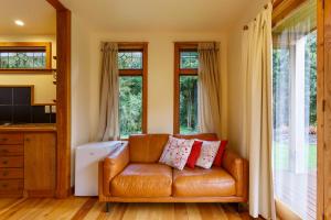 a leather couch in a living room with windows at Kahere Retreat in Franz Josef